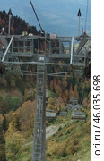 Vertical video of tourists climbing to the peaks on a ski lift, surrounded by a delightful autumn landscape. Вертикальное видео: Туристы поднимаются к вершинам на горнолыжном подъёмнике на фоне восхитительного осеннего пейзажа. Редакционное видео, видеограф Валерий Тесаков / Фотобанк Лори