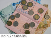 Раскрытый заграничный паспорт с отметками и лежащими на нем монетами разных стран. Редакционное фото, фотограф Свитич Олег / Фотобанк Лори