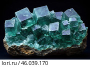 A large crystal of a mineral, probably fluorite, of a rich green-blue hue. The crystals have a clear cubic shape and look transparent with iridescent reflections. The mineral is located on a stone base, which emphasizes its natural origin. Against a dark background, the composition looks contrasting and dramatic, emphasizing the shine and depth of color. Стоковое AI-изображение, AI-художник Анна Кривицкая / Фотобанк Лори