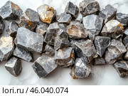 A scattering of unprocessed metallic ores with golden inclusions. The stones have a rough, uneven surface and a dark gray hue, which may indicate the presence of minerals such as galena, pyrite, or even gold-bearing rocks. The background is made in neutral light colors, which emphasizes the texture and color scheme of the stones. Стоковое AI-изображение, AI-художник Анна Кривицкая / Фотобанк Лори