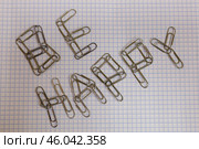 Фраза "Be happy", выложенная из металлических канцелярских скрепок на тетрадных листах. Стоковое фото, фотограф Дмитрий Кравченко / Фотобанк Лори