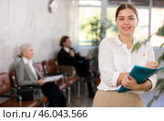 Smiling secretary girl stands at entrance to office reception and expects visitors. Стоковое фото, фотограф Яков Филимонов / Фотобанк Лори