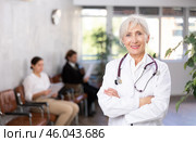 smiling mature medical female receptionist affably waiting for patients of clinic in waiting room. Стоковое фото, фотограф Яков Филимонов / Фотобанк Лори