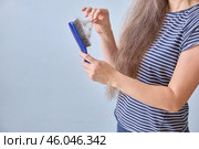 Faceless woman cleans her comb after copious hair loss. Copy space. Стоковое фото, фотограф Кутина Татьяна / Фотобанк Лори