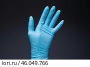 Hand wearing blue nitrile glove showing five fingers on dark background. Стоковое AI-изображение, AI-художник Иван Рябоконь / Фотобанк Лори