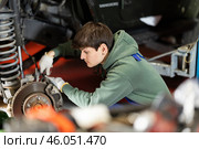 Auto mechanic connects brake hose to front wheel hub of car. Стоковое фото, фотограф Яков Филимонов / Фотобанк Лори