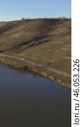 Vertical drone video of flying over a hilly rural landscape with a winding road and fish ponds. Altai Krai. Стоковое видео, видеограф Сергей Пристяжнюк (Serg Zastavkin) / Фотобанк Лори