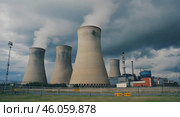 A nuclear power plant stands tall in the middle of a vast field, surrounded by greenery and under a clear sky. Стоковое AI-изображение, AI-художник Ирина Старикова / Фотобанк Лори