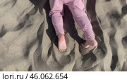 Cute baby girl playing with yellow sand on the beach by the sea. Стоковое видео, видеограф Spirit River / Фотобанк Лори