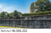 An old weathered brick wall of an ancient fort. Cannon barrels above the loopholes. A modern multi-storey building in the distance. The blue sky. Malaysia. Penang. Georgetown. Fort Cornwallis (2023 год). Стоковое фото, фотограф Вера Ивановна Кубарева / Фотобанк Лори