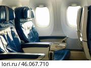 Empty seats and bright windows inside an airplane cabin during flight. Стоковое AI-изображение, AI-художник Иван Рябоконь / Фотобанк Лори