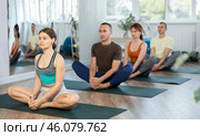 Lovers of active lifestyle on yoga mat perform doing Baddha konasana, butterfly pose in gym. Стоковое фото, фотограф Яков Филимонов / Фотобанк Лори