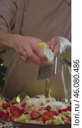 Swiss cheese is crumbled and added to a salad with tomatoes, lettuce, and other vegetables. Vertical. Стоковое видео, видеограф Strunov David / Фотобанк Лори
