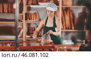 Young girl seller in apron putting fresh croissant in plastic bag in bakery shop. Стоковое видео, видеограф Яков Филимонов / Фотобанк Лори