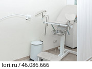 White modern gynecological examination chair for women. Medical chair in the gynecologist's office with white wall. Reproductive system and Pregnancy concept. High quality photo. Copy space. Стоковое фото, фотограф Ирина Михайличенко / Фотобанк Лори