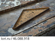 Old framing square resting on wood with peeling paint. Стоковое AI-изображение, AI-художник Иван Рябоконь / Фотобанк Лори