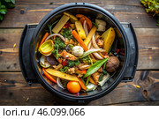 An open compost container with peels and fruit and vegetable clippings. Organic waste in a garden composter. Eco-friendly gardening, sustainability, ecology. Стоковое AI-изображение, AI-художник Photojuli / Фотобанк Лори