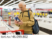 Senor man pensioner buying modern tablet digital in showroom of digital electronic goods store. Стоковое фото, фотограф Татьяна Яцевич / Фотобанк Лори
