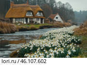 Beautiful blooms of spring snowdrops, Galanthus nivalis, by the side of the river that runs through the village with thatched cottages in the background. Стоковое AI-изображение, AI-художник Ирина Михайличенко / Фотобанк Лори