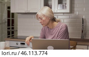Elderly woman working on laptop while experiencing fatigue. Стоковое видео, видеограф Владимир Федоров / Фотобанк Лори