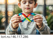 A colorful sign of the endless rainbow of autism in the hands of a boy. World Autism Awareness Day, the Autistic rights movement. Society's acceptance of autism. Стоковое AI-изображение, AI-художник Photojuli / Фотобанк Лори
