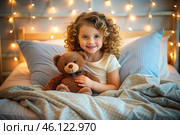 A cute curly-haired girl hugs a teddy bear, sitting in a cozy bed, a small child hugs a toy and gets ready for bed. A healthy night's sleep. Стоковое AI-изображение, AI-художник Photojuli / Фотобанк Лори