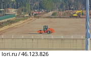 Orange road roller and yellow excavators working on a flat construction site. Стоковое видео, видеограф Константин Шишкин / Фотобанк Лори