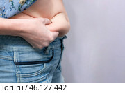 Overweight woman, large belly with folds, holds a layer of fat with a hand. Стоковое фото, фотограф Коханова Наталья / Фотобанк Лори