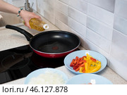 Женская рука наливает кукурузное масло из бутылки на разогретую сковородку, рядом нарезаны подготовленные овощи для жарки. Стоковое фото, фотограф Алиса Сокол / Фотобанк Лори