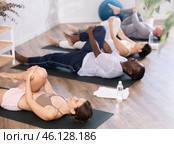 Young woman doing stretching Ardha Pawanmuktasana in yoga studio. Стоковое фото, фотограф Яков Филимонов / Фотобанк Лори