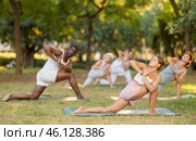 Girl performing Parivrtta Anjaneyasana in group yoga class outdoors. Стоковое фото, фотограф Яков Филимонов / Фотобанк Лори