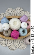 Vertical time lapse video of colorful balls of cotton yarn for hand crochet in placed by female hand in wooden plate on handmade lace napkin on light table. Wooden hooks nearby. Flat lay, close-up. Стоковое видео, видеограф Виктория Катьянова / Фотобанк Лори