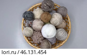 Time-lapse video of balls of beige colors wool knitting and crochet yarn being placed in wicker basket on table. Crochet hooks and knitting needles nearby. View from above, close-up, sped up. Стоковое видео, видеограф Виктория Катьянова / Фотобанк Лори