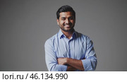 Portrait of a smiling businessman with folded arms on gray background. Стоковое видео, видеограф Данил Руденко / Фотобанк Лори