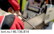 The master sharpens the chainsaw chain with a special tool. Стоковое фото, фотограф Igor Skripachev / Фотобанк Лори