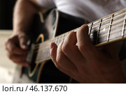 Playing the guitar. Strumming acoustic guitar. Musician plays music. Man fingers holding mediator. Man hand playing guitar neck in dark room. Unrecognizable person rehearsing, fretboard close-up. Стоковое фото, фотограф Марина Демидюк / Фотобанк Лори