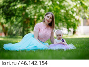 Happy mother and daughter in the park. Beauty nature scene with family outdoor lifestyle. Happy family resting together on the green grass, having fun outdoor. Happiness and harmony in family life. Стоковое фото, фотограф Иван Карпов / Фотобанк Лори
