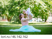 Young mother with child in park sitting on grass on a summer day. Lifts the child into the air. The concept of right relationships. Стоковое фото, фотограф Иван Карпов / Фотобанк Лори