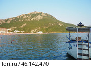 Canj, Montenegro 07.20.2024 Boats and a shore with vacationers, sunbathers and swimmers. Hotels, sun umbrellas, Adriatic waves, buoys. Beach tourism. Vacation travel. Summer day. Pebble rock beach. Редакционное фото, фотограф Юлия Петровская / Фотобанк Лори