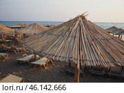 Canj, Montenegro: 07.20.2024 Sun loungers and straw umbrellas line the shore at Bar Beach, creating a serene atmosphere for relaxation by the calm waters on a sunny day. Adriatic Mediterranean Sea. Редакционное фото, фотограф Юлия Петровская / Фотобанк Лори