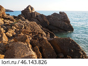Waves gently crash against the rugged rocks while the sun sets over the horizon. Experience the serene beauty of this coastal location filled with natural wonders. Canj, Montenegro, Adriatic sea (2024 год). Стоковое фото, фотограф Юлия Петровская / Фотобанк Лори