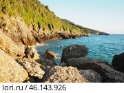 Waves gently crash against the rugged rocks while the sun sets over the horizon. Experience the serene beauty of this coastal location filled with natural wonders. Canj, Montenegro, Adriatic sea (2024 год). Стоковое фото, фотограф Юлия Петровская / Фотобанк Лори
