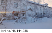 An abandoned building in Vorkuta, surrounded by snowdrifts and snow-covered trees. The building's façade is cracked, some of the plaster has fallen off, and the windows are broken or boarded up. It is clear that the place has not been used for a long time and is in a state of disrepair.The trees in front of the building are covered with frost and snow, which creates an atmosphere of cold and abandonment. Judging by the architecture, this could have been a residential building or a former public building. The ruined walls, the entrance covered in snow, and the lack of traces of people emphasize the desolation of this area.This landscape is typical for Vorkuta, where there are many abandoned houses left after the mass exodus of the population from the city. Vorkuta is one of the harshest cities in Russia, where winter lasts most of the year, and natural conditions leave no chance for the rapid destruction of buildings. (2021 год). Редакционное фото, фотограф Анна Кривицкая / Фотобанк Лори