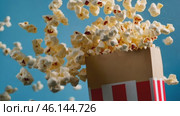 Red white stripe box of popcorn. Popcorn floating out of the paper box, isolated on a light blue background. Striped retro bucket with freshly popped popcorn with some pieces flying. Snack food. Стоковое AI-видео, аниматор Марина Демидюк / Фотобанк Лори