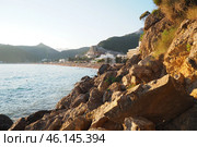 Waves gently crash against the rugged rocks while the sun sets over the horizon. Experience the serene beauty of this coastal location filled with natural wonders. Canj, Montenegro, Adriatic sea (2024 год). Стоковое фото, фотограф Юлия Петровская / Фотобанк Лори