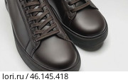Dark brown leather lace-up running shoes with low tops, thick soles. The laces and black rubber outsole. Sporty look. Men to wear during outdoor activities, hiking. Brown shoes. Trendy Male Boots Pair. Стоковое AI-видео, аниматор Марина Демидюк / Фотобанк Лори