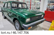Retro car "AZLK Moskvich-2140", painted in a rich green color. This Soviet-made car was produced at the Moscow Automobile Plant (AZLK) in the 1970-1980s. The car is in the USSR Museum, surrounded by display cases with porcelain figurines, crystal and other items of Soviet life.Classic Soviet car with a characteristic design.Green body paint, shiny chrome bumper.The signature "AZLK" emblem and the "Moskvich-2140" model on the front.Museum setting, glass display cases with items from the Soviet era.Caution, wet floor! - warning sign on the floor.Retro-style museum interior with red design elements. (2023 год). Редакционное фото, фотограф Анна Кривицкая / Фотобанк Лори