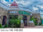 The Taigan cafe is located in the Taigan Lion Park in Crimea. The building is built in the style of a castle with stone trim, decorative white balustrades and a domed roof. Above the entrance there is a sign with the name of the cafe in Russian. Ornamental plants grow around the building, and in front of the entrance there are statues of white lions, which symbolize the theme of the park. The sky is covered with clouds, creating a picturesque atmosphere. (2023 год). Редакционное фото, фотограф Анна Кривицкая / Фотобанк Лори