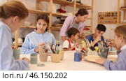 Interested children of different ages painting ceramic objects with teacher in art studio. Стоковое видео, видеограф Яков Филимонов / Фотобанк Лори