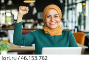 Muslim middle eastern woman in office with raised fist of empowerment, strength and women solidarity, International Womens Day concept. Стоковое AI-изображение, AI-художник Анастасия Золотницкая / Фотобанк Лори